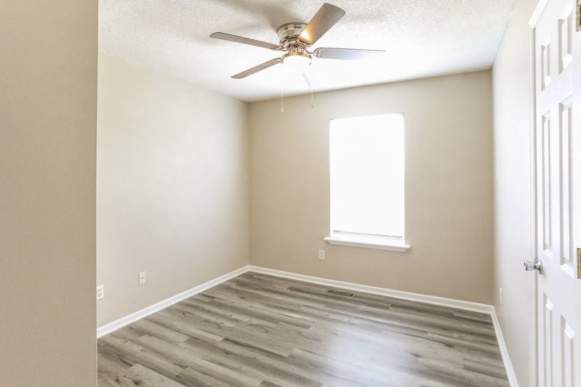 an empty room with a ceiling fan and a window