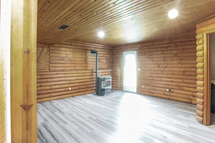 an empty log cabin with a wood stove