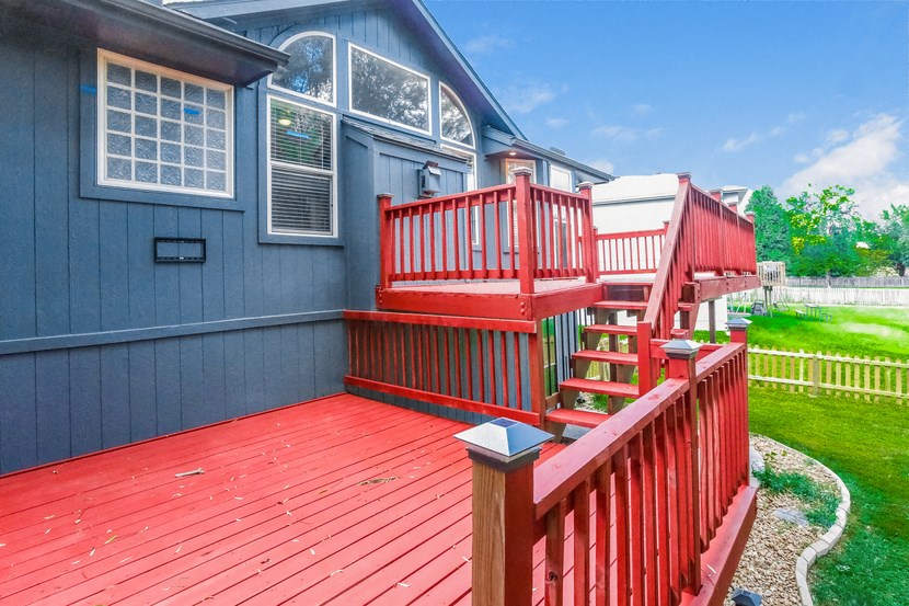 a red deck in front of a blue house
