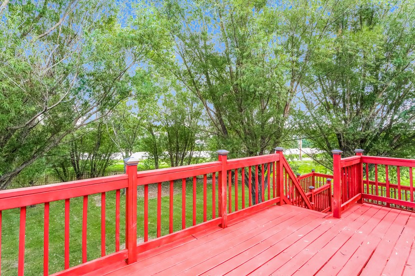 a red railing on a red deck with trees in the background