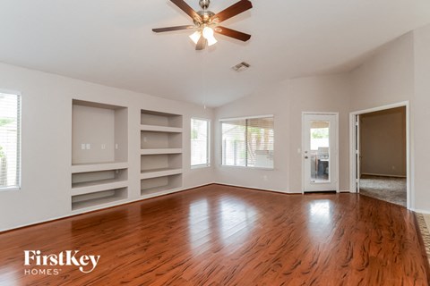 an empty living room with wood floors and a ceiling fan