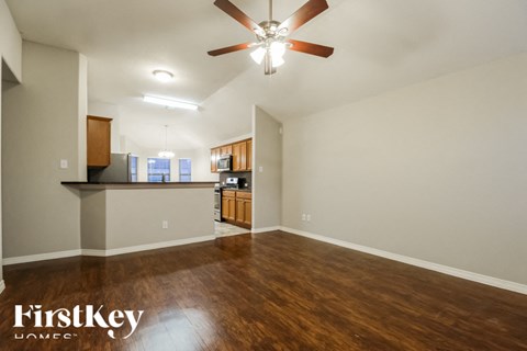 A spacious room with a ceiling fan and wooden flooring.