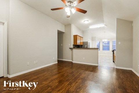A spacious room with wooden floors and a ceiling fan.