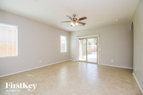 an empty living room with a ceiling fan and a door to a patio