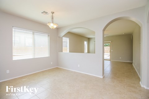 an empty dining room with white walls and tile floors