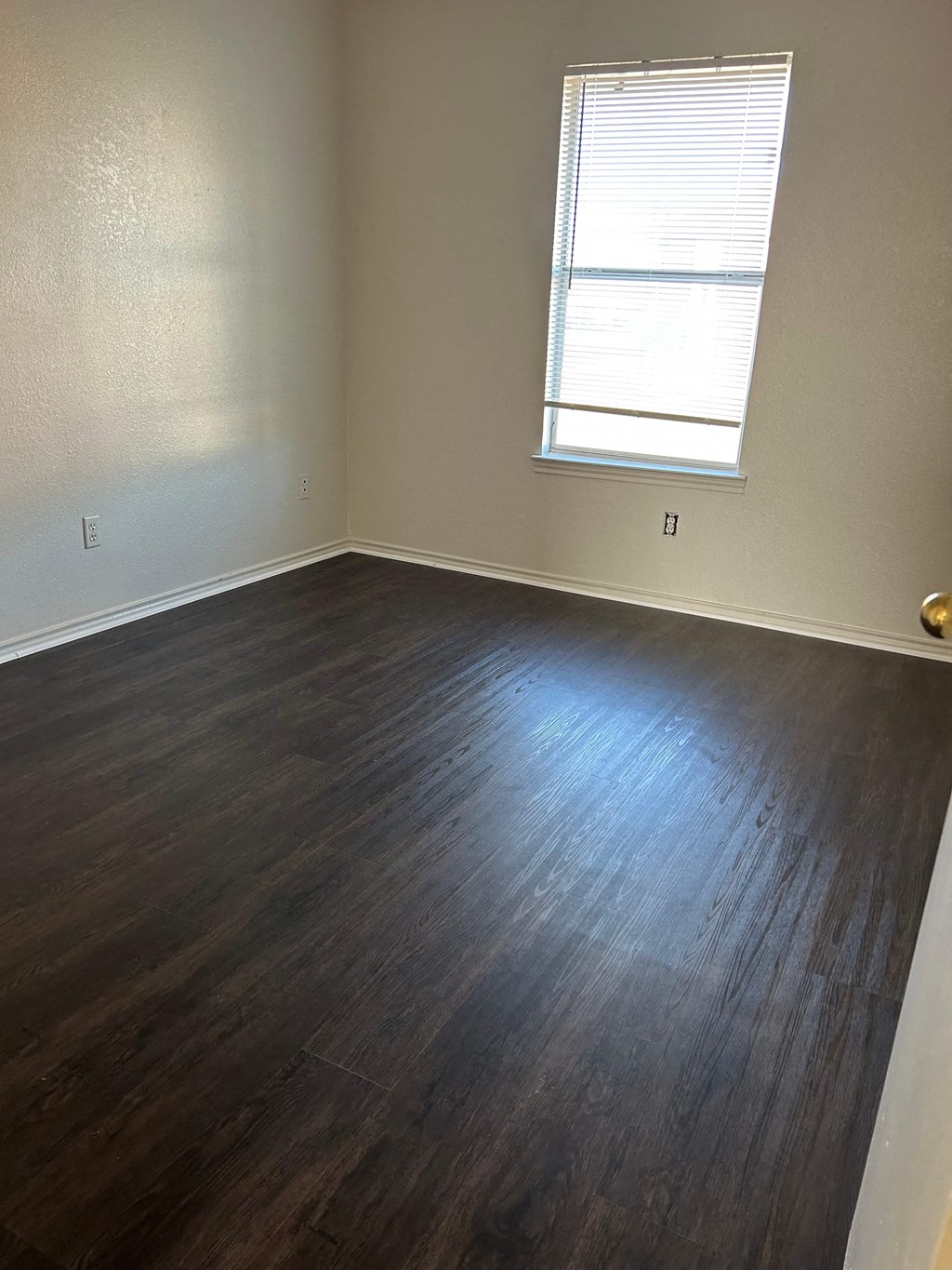 an empty room with wood floors and a window