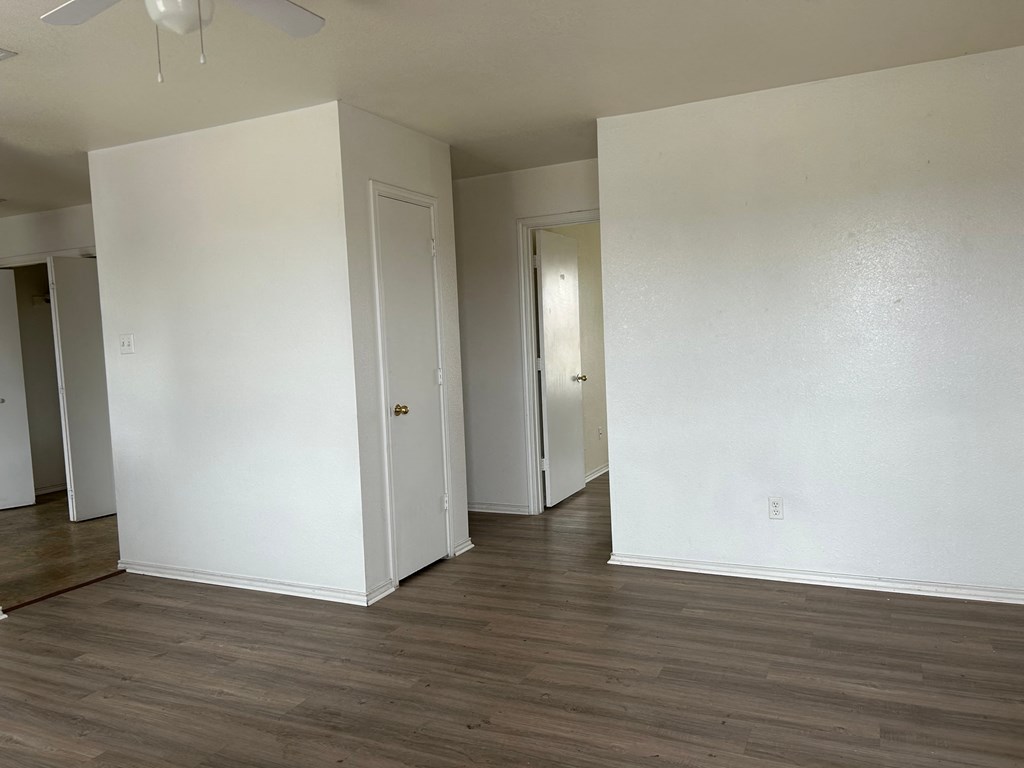 an empty living room with white walls and a wood floor