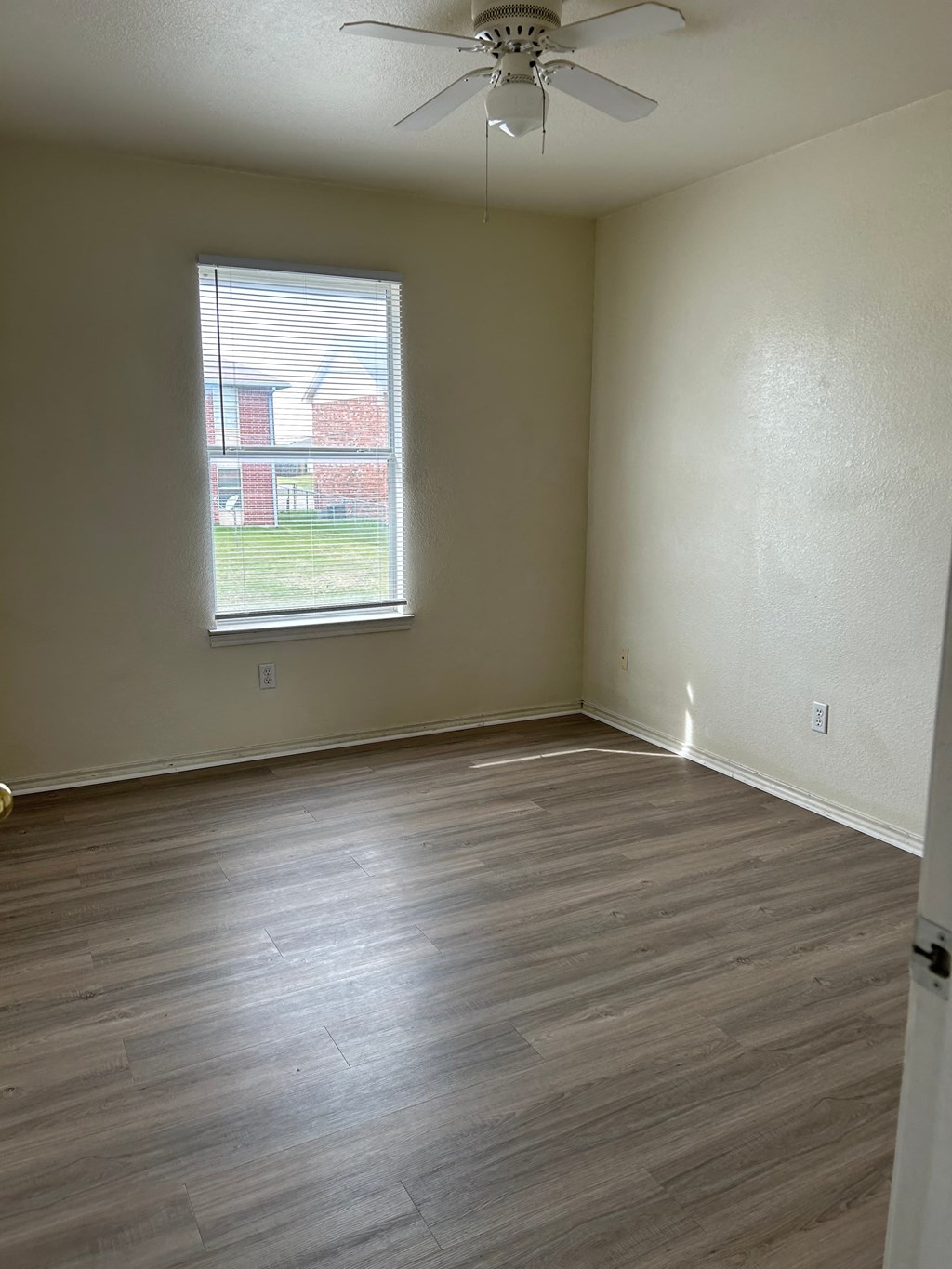 an empty living room with wooden floors and a window
