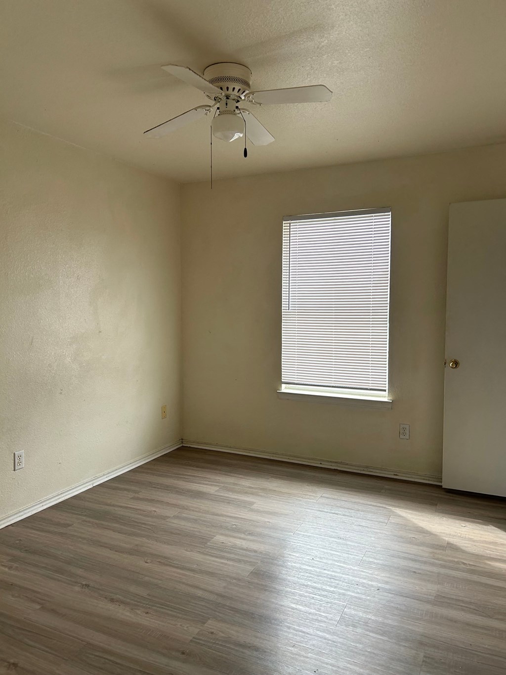 an empty room with a ceiling fan and a window
