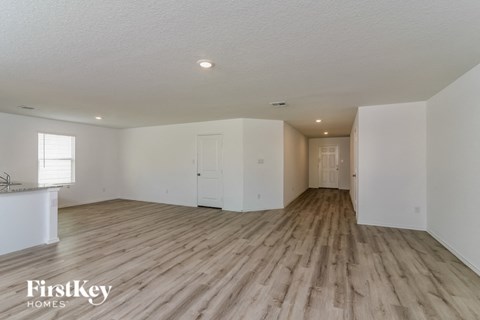 A spacious room with wooden flooring and white walls, branded with "FirstKey Homes".
