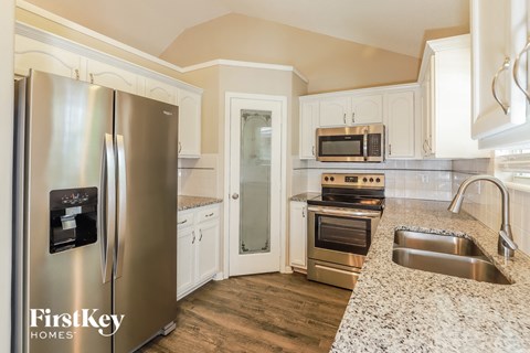 A kitchen with a stainless steel refrigerator and a granite countertop.