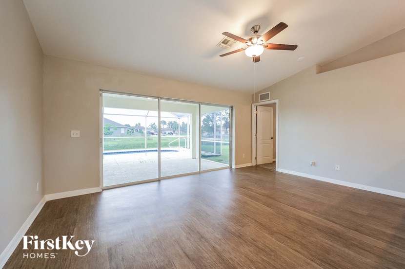 an empty living room with sliding glass doors and a ceiling fan