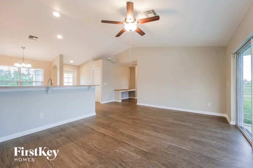 an empty living room and kitchen with a ceiling fan