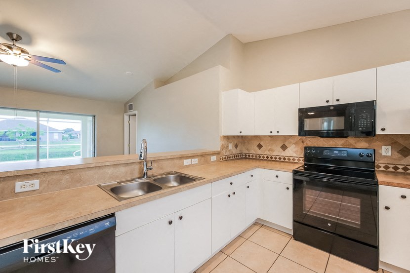 a kitchen with white cabinets and black appliances and a sink
