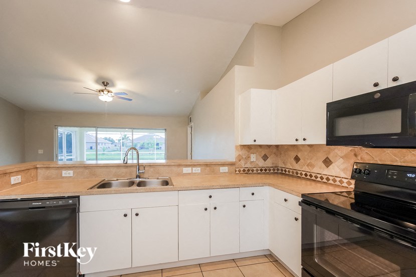 a kitchen with white cabinets and black appliances and a sink