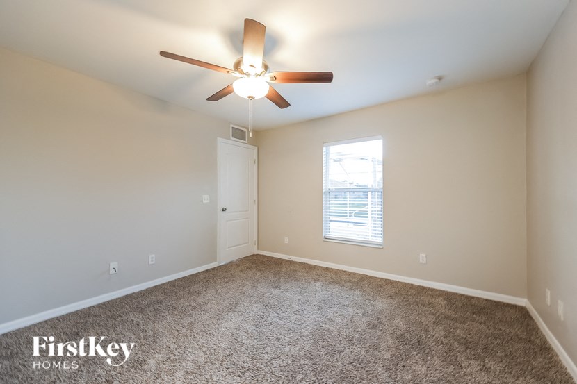 an empty living room with a ceiling fan and a window