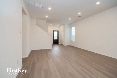 A spacious room with wooden flooring and a door at the end.
