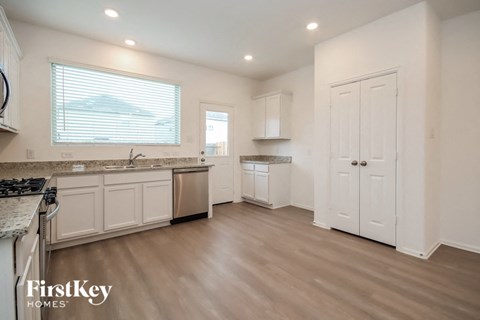 A kitchen with a stove top oven and a window with blinds.