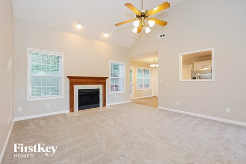 A spacious living room with a fireplace and a ceiling fan.