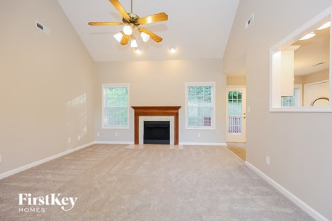 A spacious living room with a fireplace and a ceiling fan.
