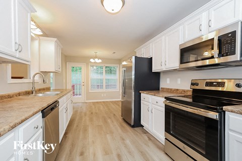 A kitchen with a black refrigerator and stainless steel appliances.