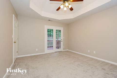 A spacious room with a ceiling fan and a door leading to a balcony.
