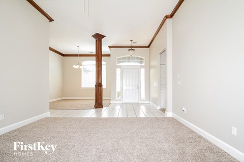 an empty living room with carpet and a white door