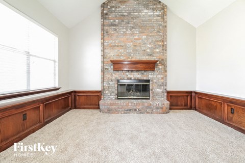 an empty living room with a brick fireplace and a window