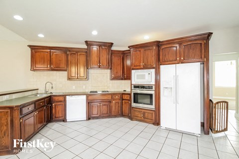 a large kitchen with wooden cabinets and white appliances