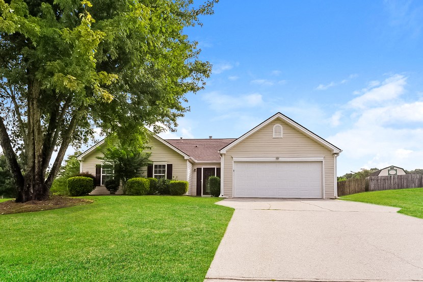 a beige house with a white garage door and a lawn