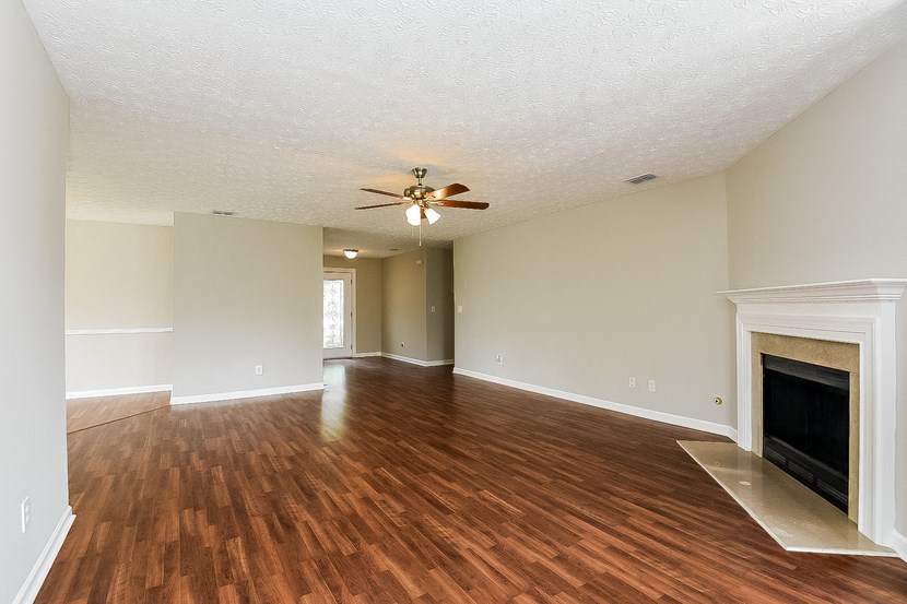 an empty living room with a fireplace and a ceiling fan