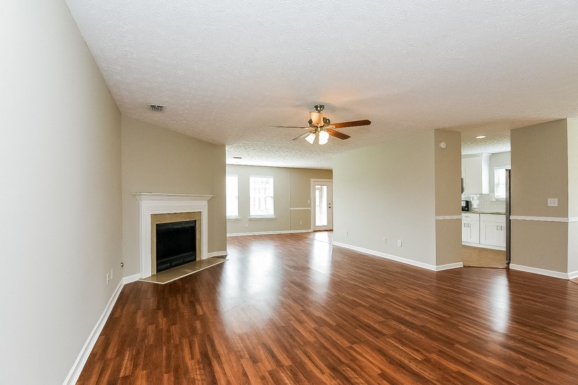an empty living room with a fireplace and a ceiling fan
