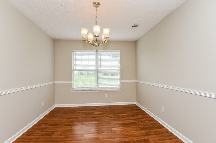 an empty dining room with wood floors and a window