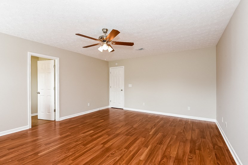 an empty living room with wood floors and a ceiling fan