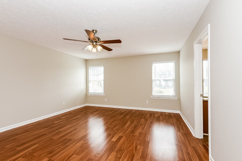 an empty living room with wood floors and a ceiling fan