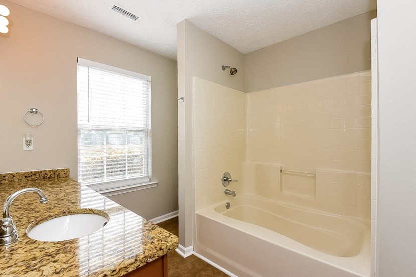 a bathroom with a tub and a sink and a window