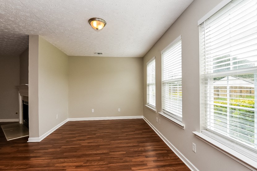an empty living room with wood flooring and large windows