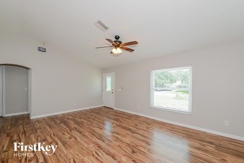 A room with a ceiling fan and wooden flooring.