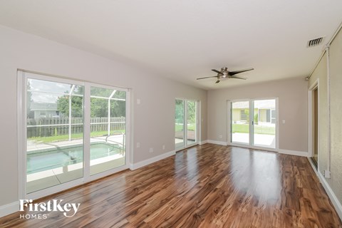 A spacious room with wooden floors and a ceiling fan.