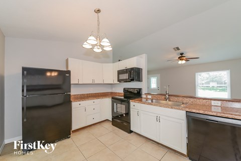 A kitchen with a black fridge, microwave, and stove top oven.