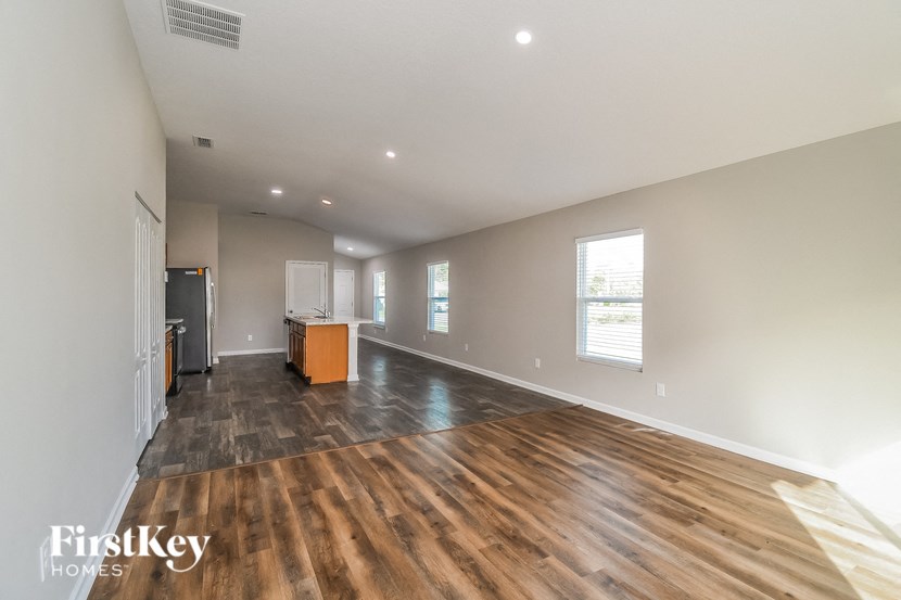 A spacious room with wooden flooring and a refrigerator in the corner.