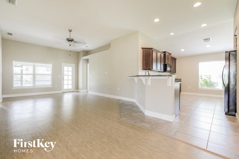 an empty kitchen and living room with a refrigerator and a counter