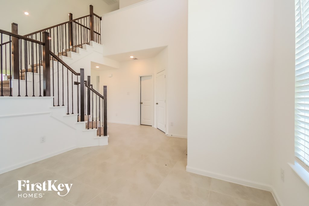A spacious hallway with a staircase and a door leading to another room.