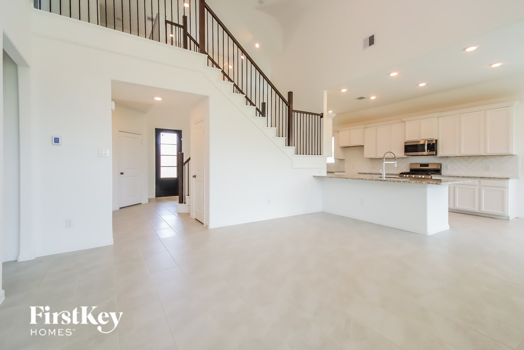 A spacious, empty living room with a staircase leading to the upper floor.