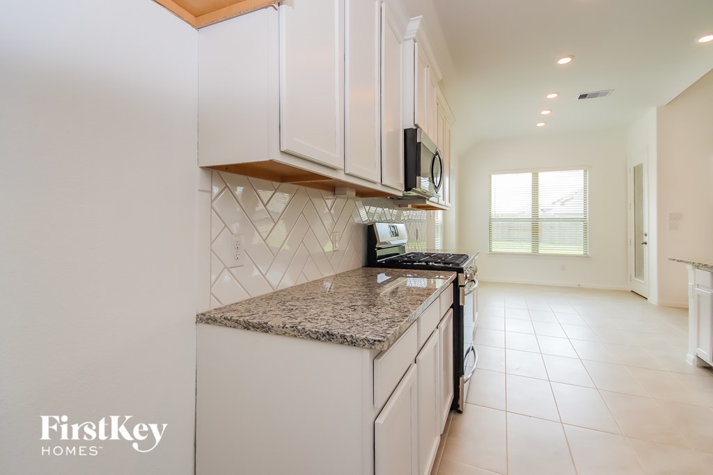 A kitchen with white cabinets and a granite countertop.