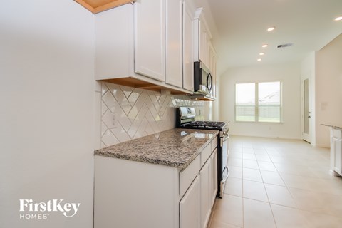 A kitchen with white cabinets and a granite countertop.