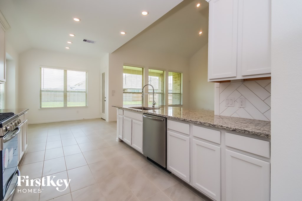 A kitchen with white cabinets and a marble countertop.