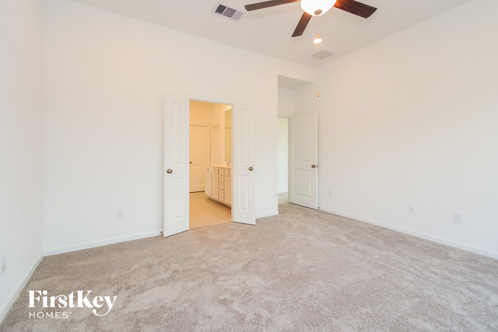 A spacious room with a carpeted floor and a ceiling fan.