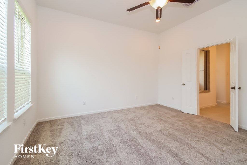 A spacious room with a carpeted floor and a ceiling fan.