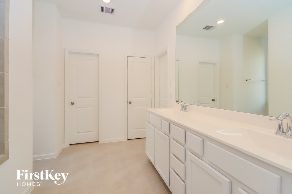 A white bathroom with a mirror and two doors.